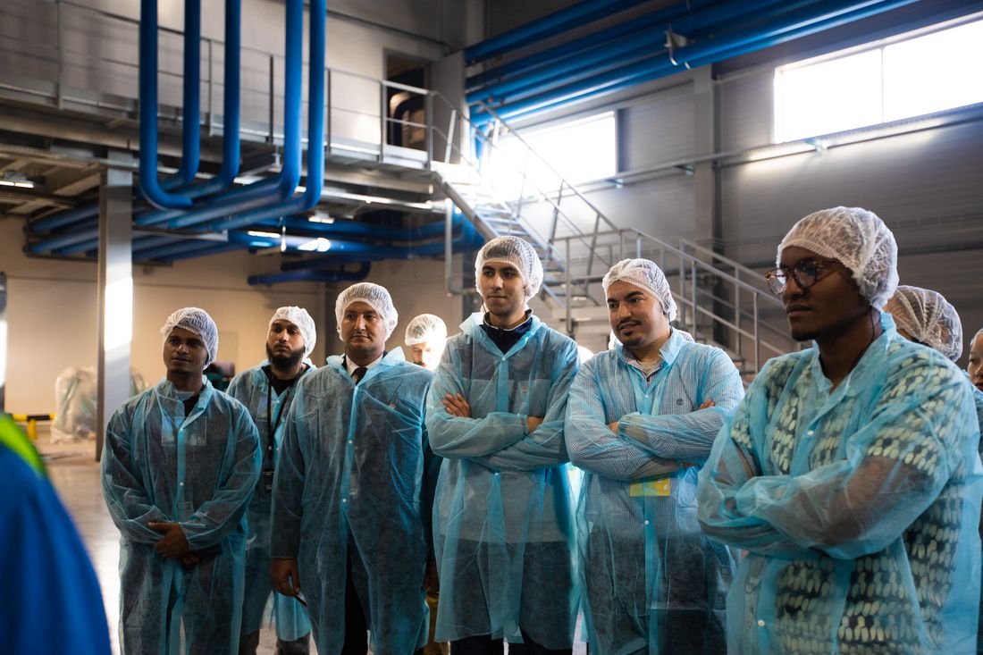 Visitors in hairnets and coveralls on a plant floor tour