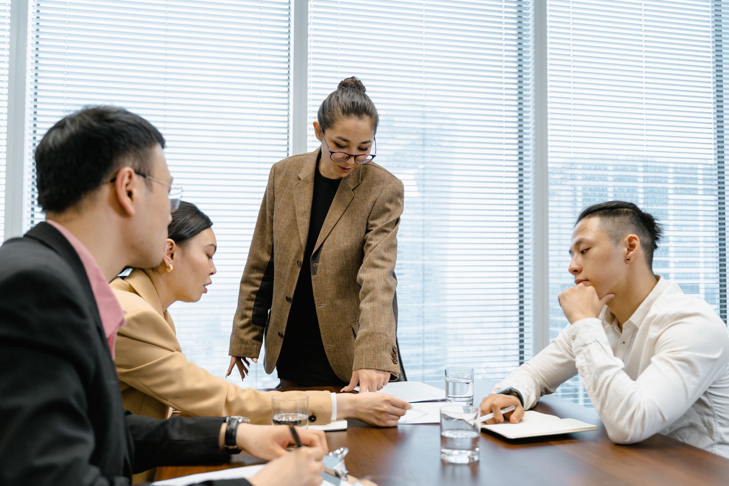 A young executive leading a working session with three colleagues around a conference table, reviewing documents together